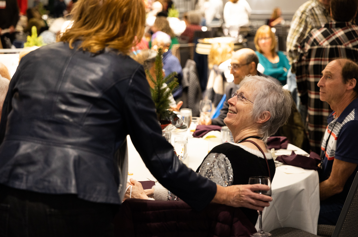 An attendee greets a seated friend.