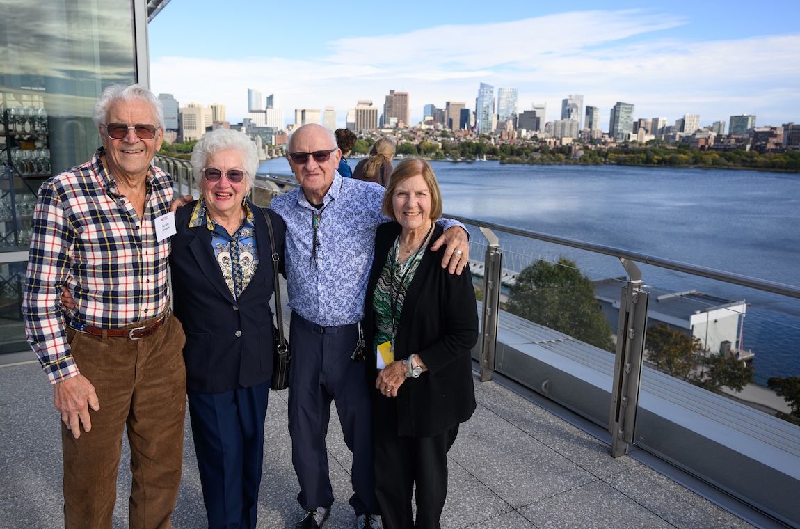 Gilbert Gagnon, Gloria Lucas, Hank Zeuli, and Terri Coyle with big smiles stand outside in front of a view of Boston's skyline