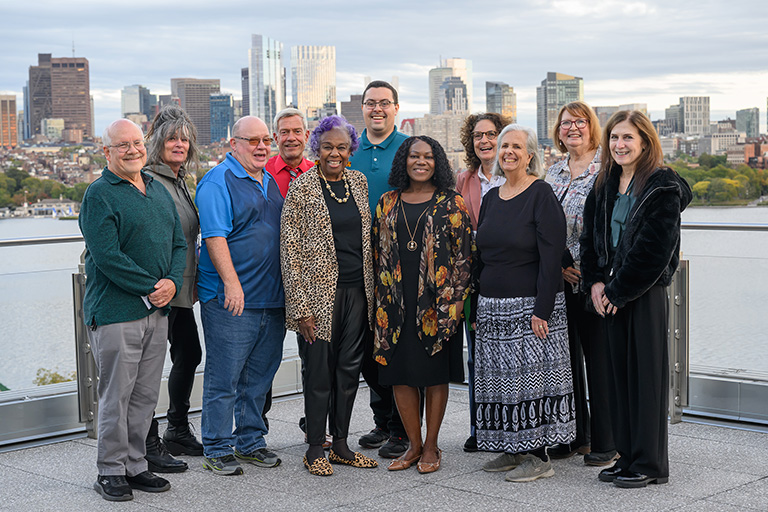 The QCC Board gathers on the balcony at the Samberg Center, Boston's skyline in the background.