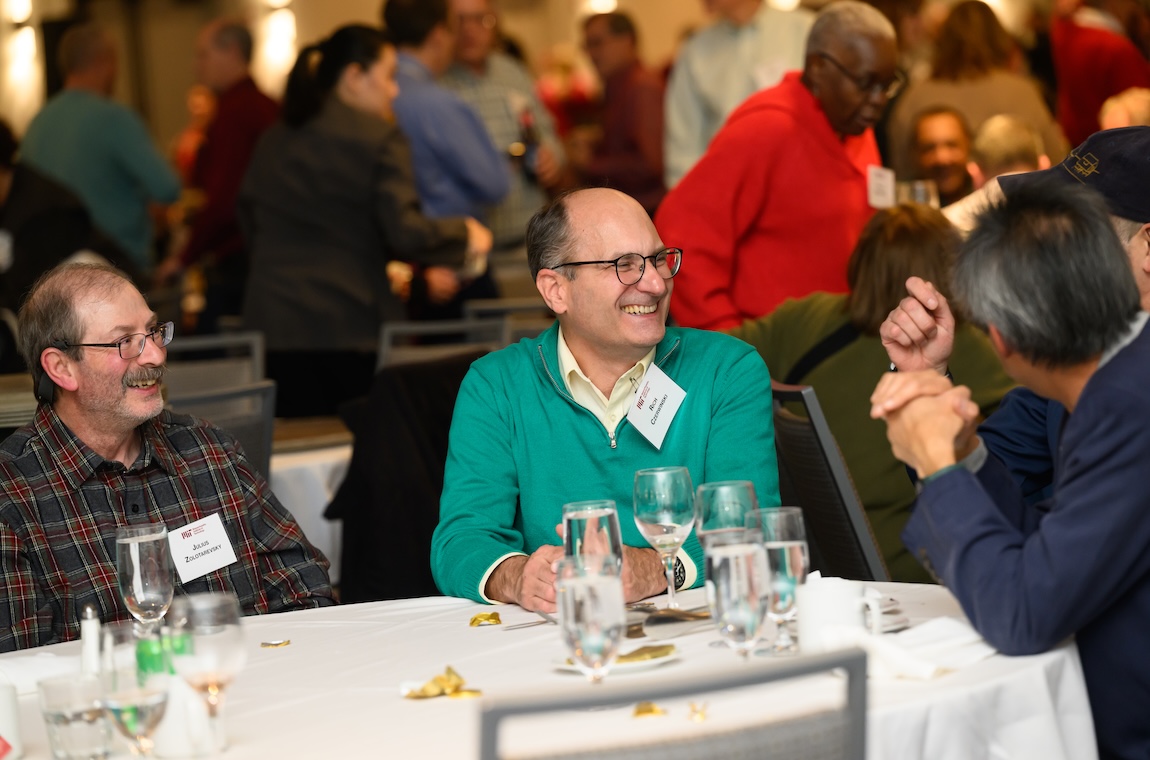 Julius Zolotarevsky and Rich Czerwinski smile and look at a guest facing away from view