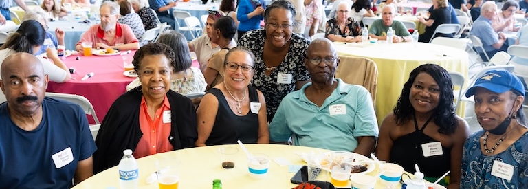 Guests of the barbecue pose at their table for a smiling photo.