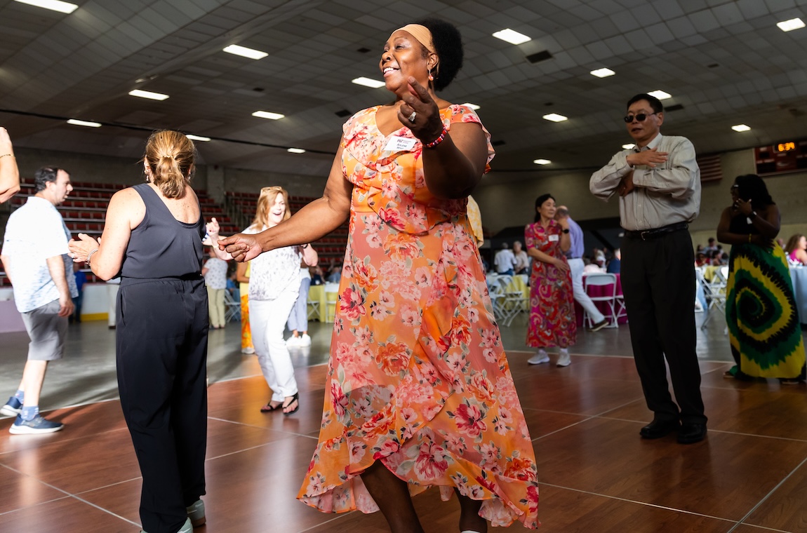 Arlene Wint dances in a long orange and pink dress as the sun shines through a window